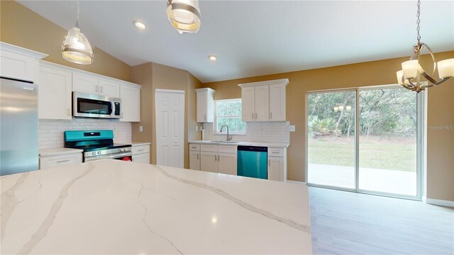 kitchen featuring a sink, decorative backsplash, vaulted ceiling, appliances with stainless steel finishes, and white cabinetry