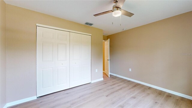 unfurnished bedroom with visible vents, a closet, light wood finished floors, baseboards, and ceiling fan