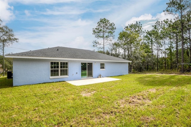 back of property with a lawn, a shingled roof, a patio, and stucco siding