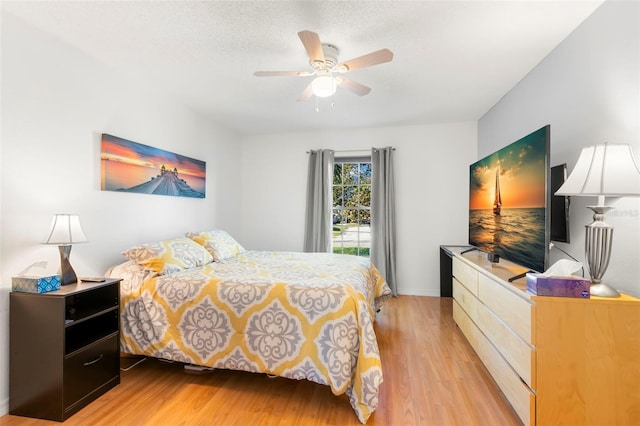 bedroom featuring light wood-style floors, ceiling fan, and a textured ceiling