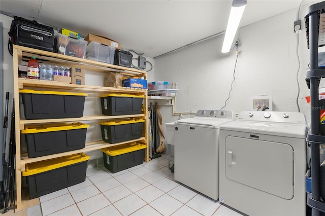 laundry room featuring washer and clothes dryer, laundry area, concrete block wall, and light tile patterned floors