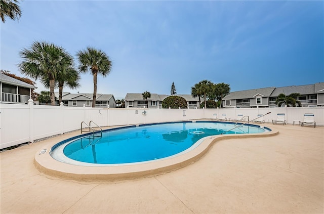 community pool featuring a residential view, a patio, and a fenced backyard