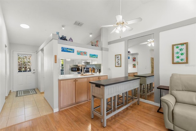 kitchen featuring ceiling fan, visible vents, open floor plan, and vaulted ceiling