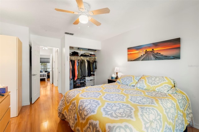 bedroom with light wood finished floors, visible vents, a closet, and ceiling fan