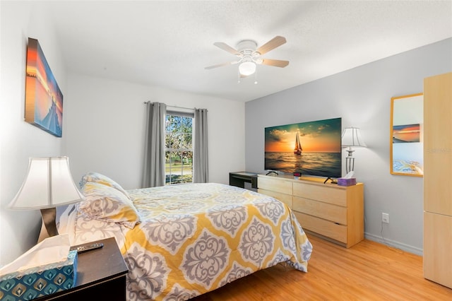 bedroom with a textured ceiling, a ceiling fan, light wood-type flooring, and baseboards