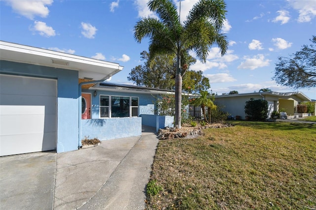2451 Baywood Dr W, Dunedin, FL 34698 - view of side of property featuring roof mounted solar panels, stucco siding, a yard, and a garage