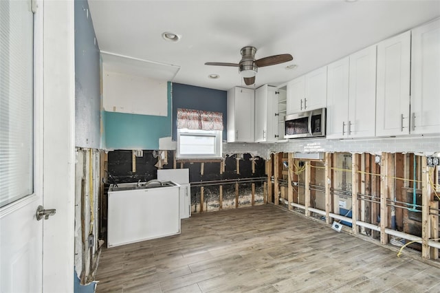 2451 Baywood Dr W, Dunedin, FL 34698 - kitchen with open shelves, stainless steel microwave, white cabinetry, light wood-style floors, and ceiling fan
