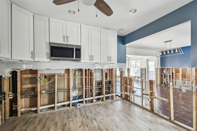2451 Baywood Dr W, Dunedin, FL 34698 - kitchen with a ceiling fan, stainless steel microwave, backsplash, wood finished floors, and white cabinets