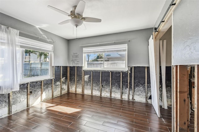 2451 Baywood Dr W, Dunedin, FL 34698 - empty room with a barn door, a ceiling fan, and wood finish floors