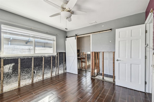 2451 Baywood Dr W, Dunedin, FL 34698 - unfurnished bedroom with wood finish floors, a barn door, visible vents, and a ceiling fan