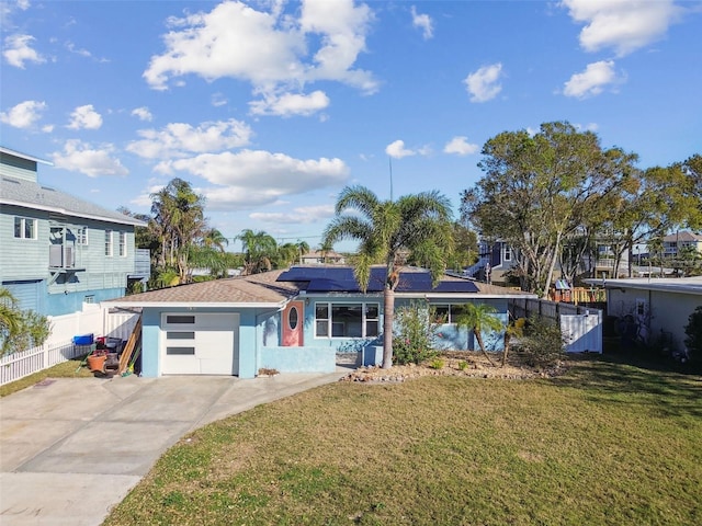2451 Baywood Dr W, Dunedin, FL 34698 - view of front facade featuring fence, driveway, solar panels, a front lawn, and a garage