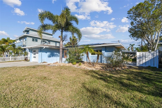 2451 Baywood Dr W, Dunedin, FL 34698 - exterior space with a front lawn, driveway, fence, an attached garage, and solar panels