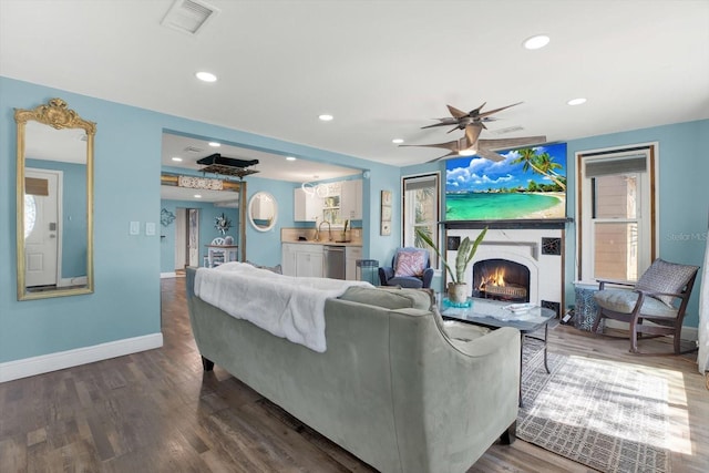 living area with visible vents, baseboards, a lit fireplace, recessed lighting, and wood finished floors