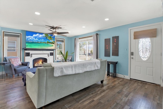 living area featuring dark wood-type flooring, plenty of natural light, recessed lighting, and a lit fireplace