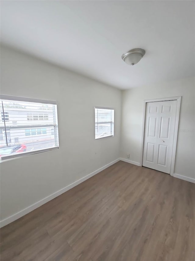 unfurnished bedroom with a closet, baseboards, and wood finished floors