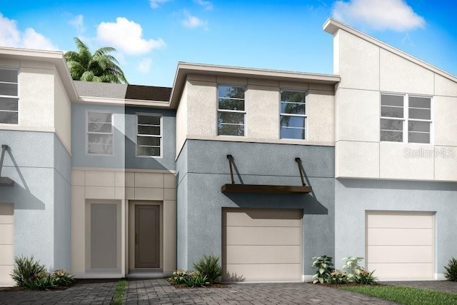 view of front of house featuring stucco siding, an attached garage, and decorative driveway