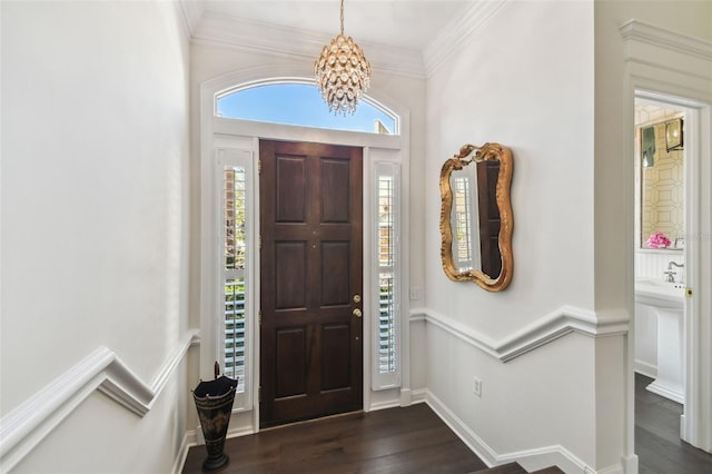 entrance foyer with a notable chandelier, ornamental molding, and dark wood-style flooring