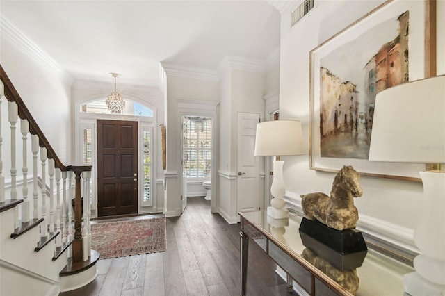 foyer featuring crown molding, hardwood / wood-style flooring, stairway, and a chandelier