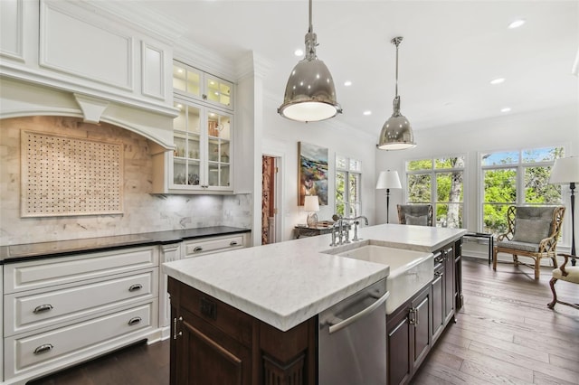 kitchen featuring crown molding, decorative backsplash, stainless steel dishwasher, white cabinetry, and a sink