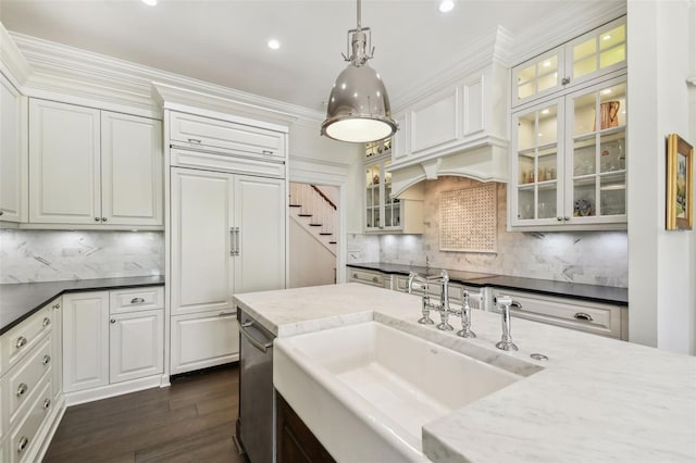 kitchen with paneled fridge, dark wood finished floors, a sink, pendant lighting, and crown molding