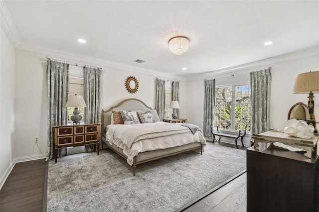 bedroom featuring visible vents, baseboards, wood finished floors, and crown molding