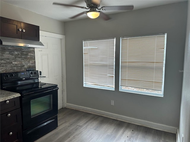 kitchen featuring under cabinet range hood, baseboards, black range with electric stovetop, and light wood-style flooring