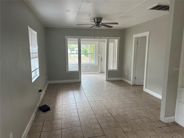 unfurnished room with light tile patterned floors, baseboards, visible vents, and ceiling fan