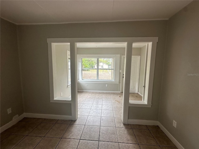 tiled empty room featuring baseboards