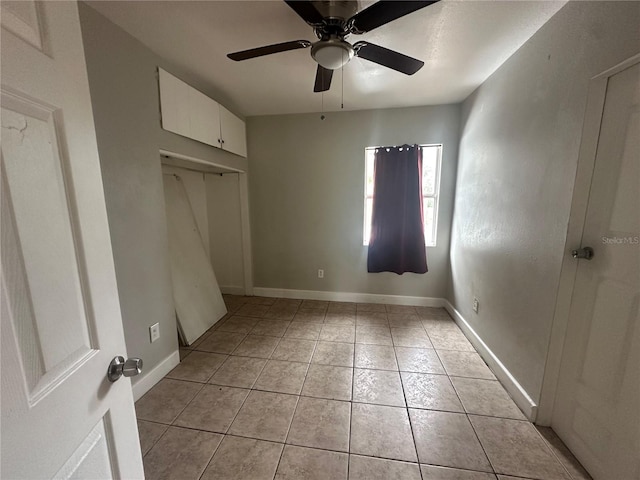 unfurnished bedroom featuring light tile patterned floors, baseboards, a closet, and ceiling fan