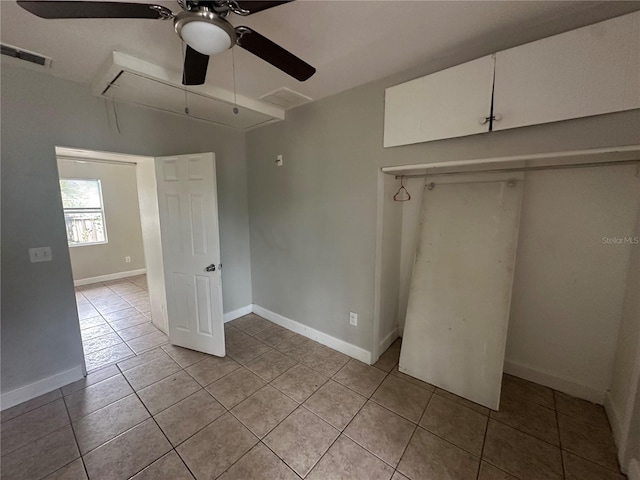 unfurnished bedroom with attic access, light tile patterned floors, visible vents, and a closet