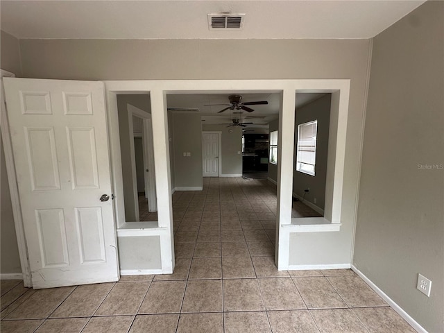 corridor with visible vents, baseboards, and light tile patterned flooring