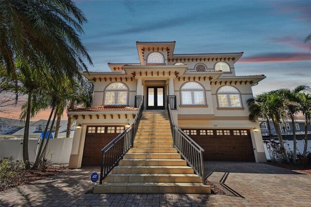 mediterranean / spanish-style house featuring stairway, stucco siding, french doors, decorative driveway, and a garage