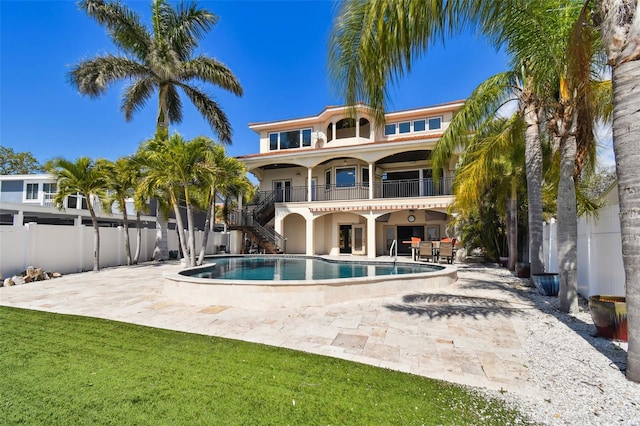 rear view of house with fence, stairway, stucco siding, a community pool, and a patio
