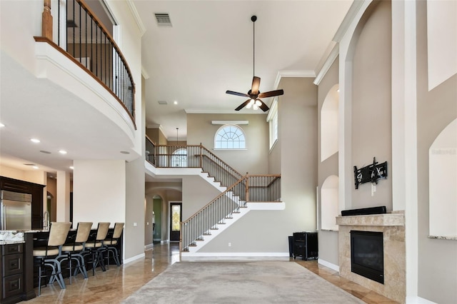 living area with visible vents, a healthy amount of sunlight, ceiling fan, and ornamental molding