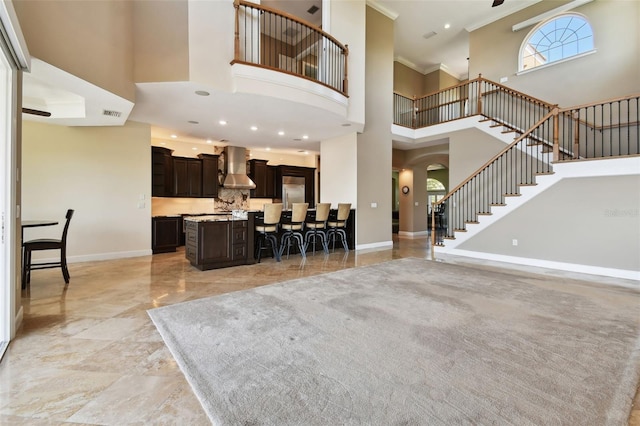living room with a towering ceiling, stairs, baseboards, and ornamental molding