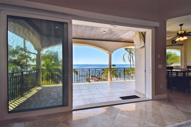 doorway with baseboards, a ceiling fan, and a water view