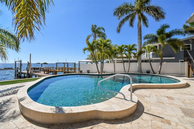pool featuring a patio, fence, a dock, and a water view