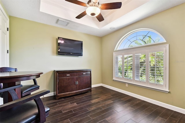 home office with wood finish floors, visible vents, a ceiling fan, a tray ceiling, and baseboards