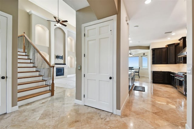 entryway featuring stairway, baseboards, a fireplace, and a ceiling fan