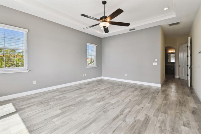 spare room featuring plenty of natural light, a ceiling fan, and a tray ceiling
