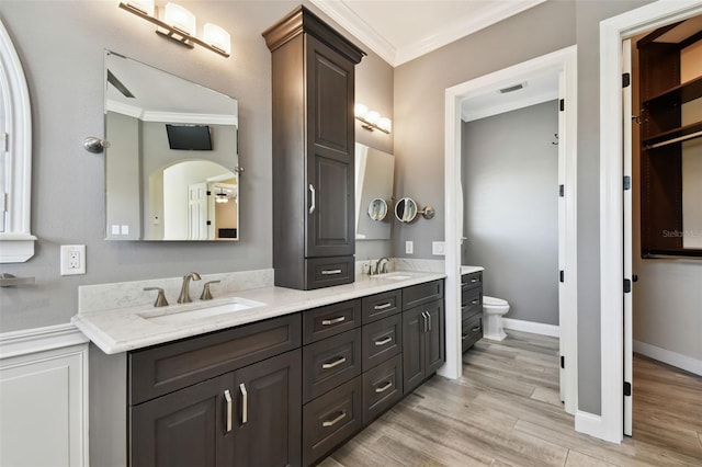 full bathroom with a sink, toilet, wood finished floors, and crown molding