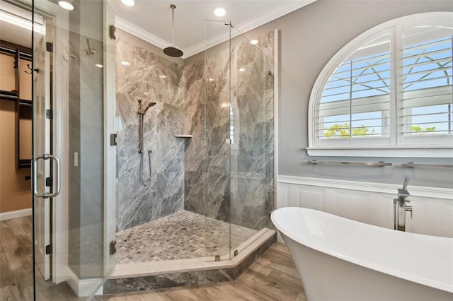 full bathroom featuring a marble finish shower, a wainscoted wall, wood finished floors, ornamental molding, and a freestanding tub