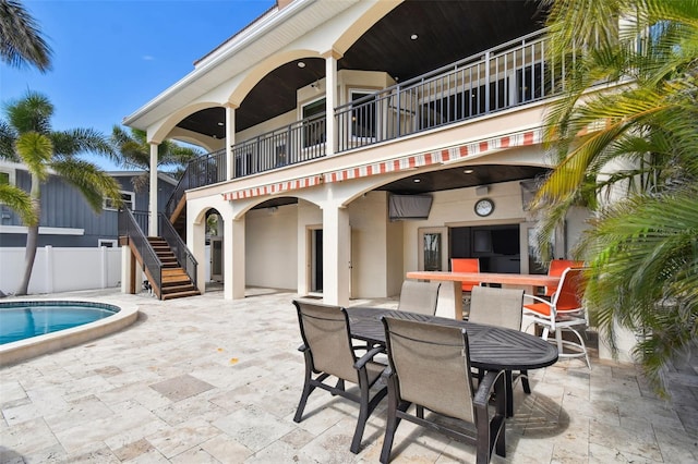 view of patio / terrace featuring a fenced in pool, fence, stairs, a balcony, and outdoor dining space