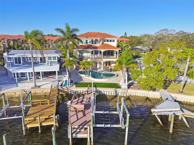 dock area with a balcony, an outdoor pool, a patio, and a water view