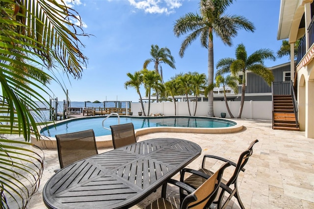 pool featuring stairway, fence, outdoor dining space, and a patio area