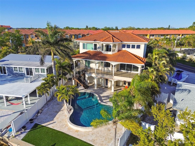 rear view of house featuring a tile roof, a fenced backyard, stairway, a fenced in pool, and a patio area