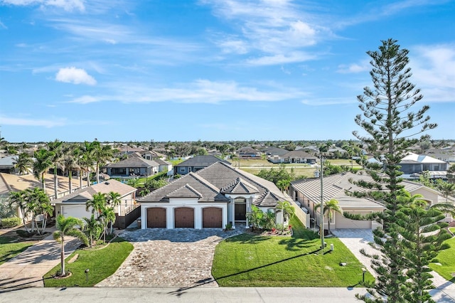 view of front of property with decorative driveway, a front lawn, an attached garage, and a residential view