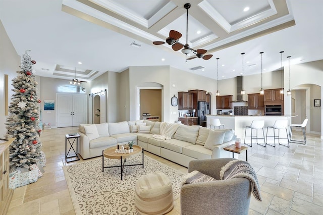 living room featuring arched walkways, stone tile floors, coffered ceiling, and a towering ceiling