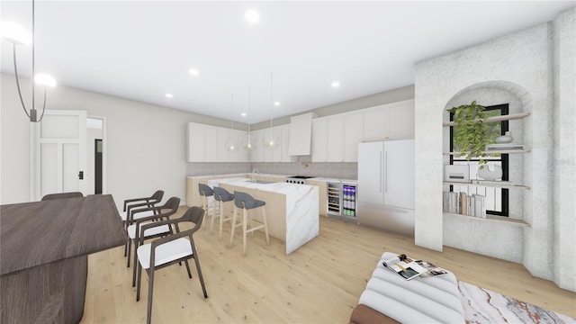 kitchen with white cabinetry, light wood finished floors, a kitchen island with sink, and freestanding refrigerator