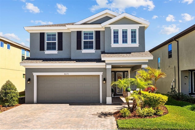 view of front of property featuring decorative driveway, an attached garage, and stucco siding